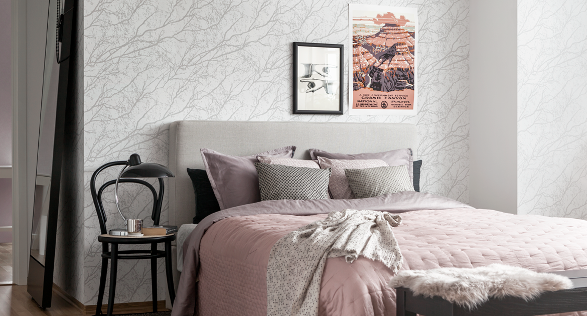 Sovrum med säng i grått och rosa. Tapet med trädmönster. Inspirationsbild.