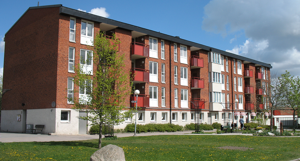 Trevåningshus i tegel med röda balkonger på Varbergagatan 99