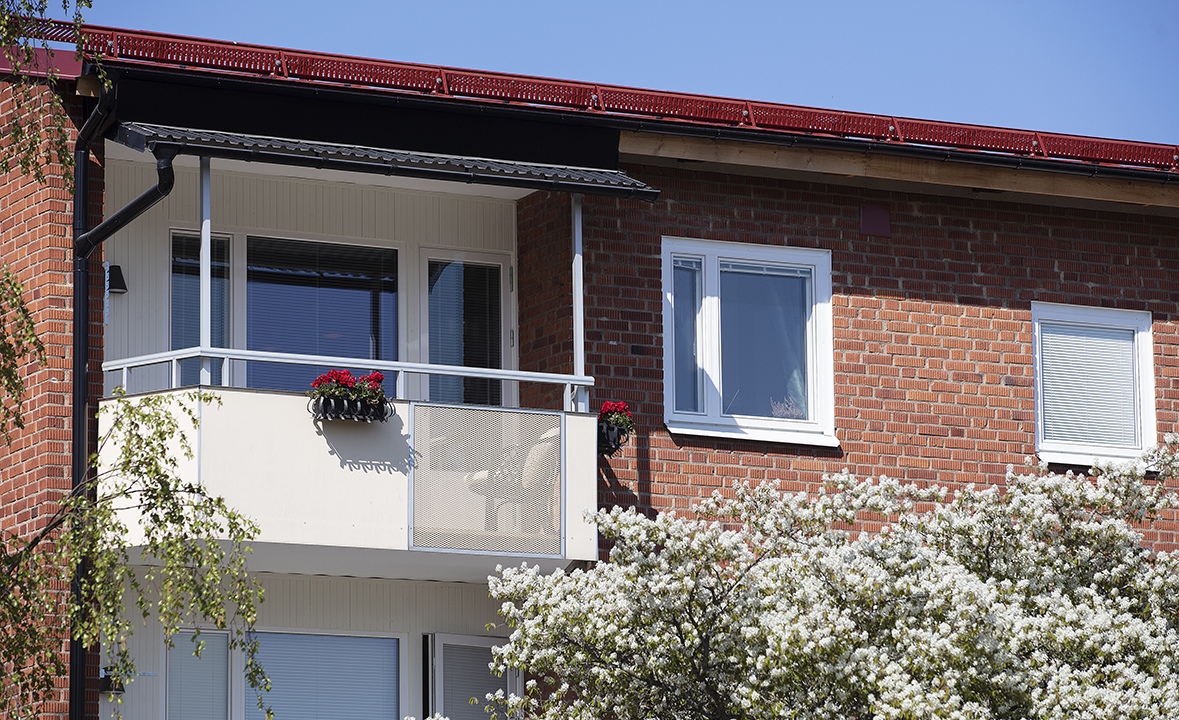 Tegelhus med balkong och vackra blomlådor med röda blommor