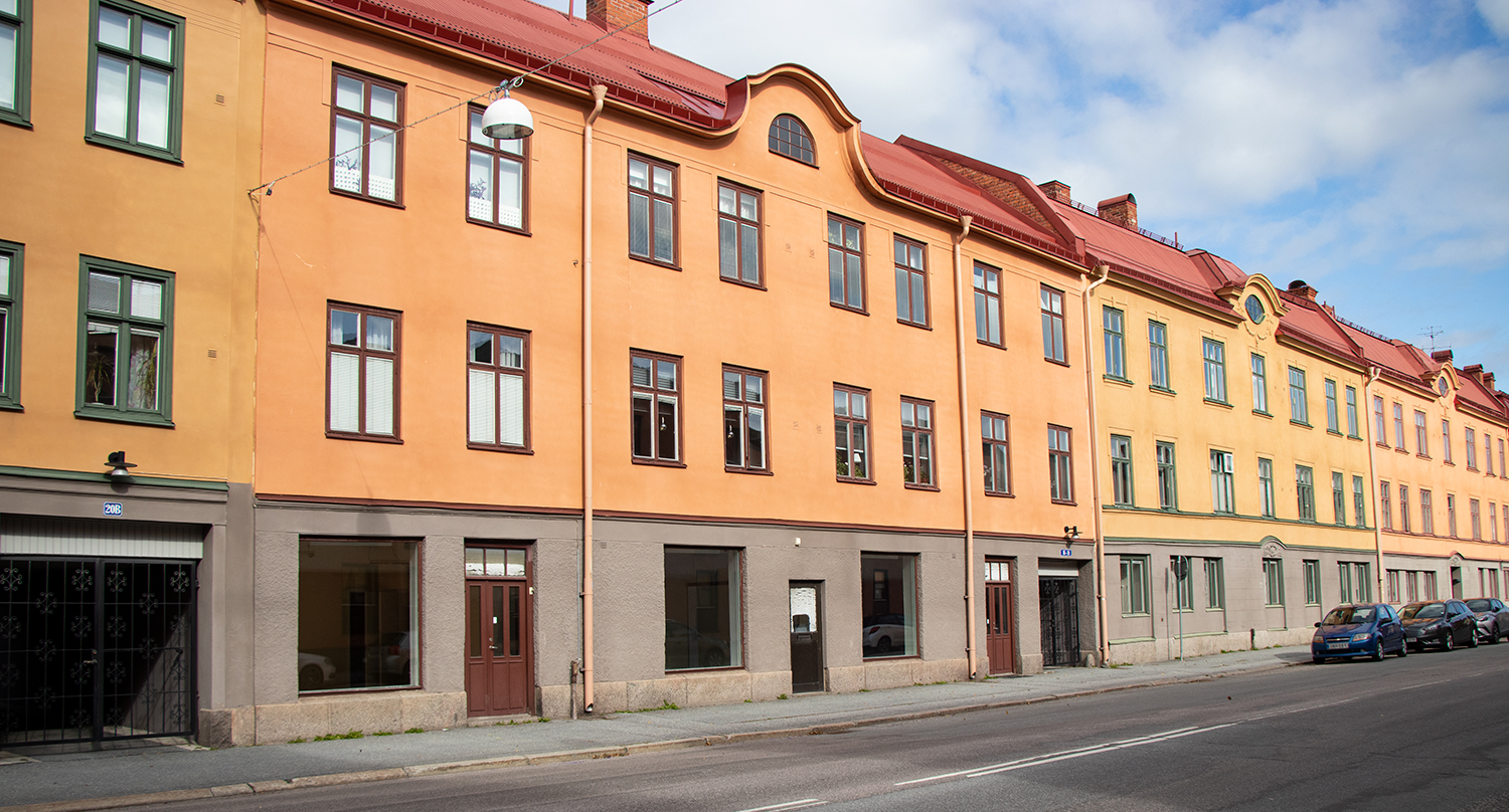 Sekelskifteshus med gul putsad fasad i tre våningar med lokaler i bottenplan.