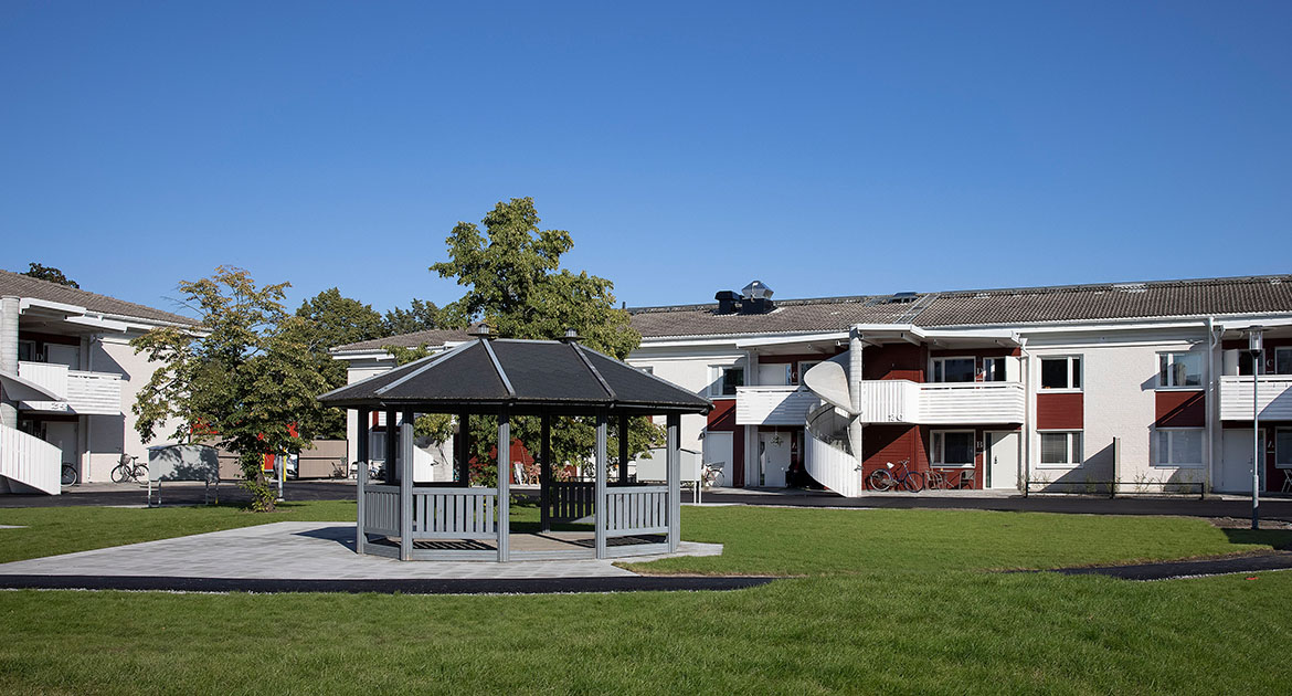 Pergola på innergård med vida tvåvåningshus bakom