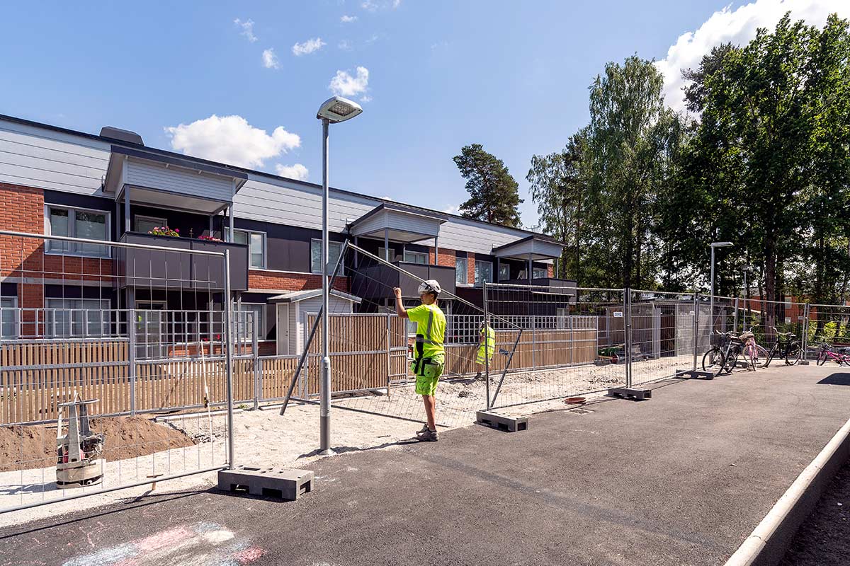 Byggarbetare arbetar med att sätta upp stängsel framför hus i Vivalla