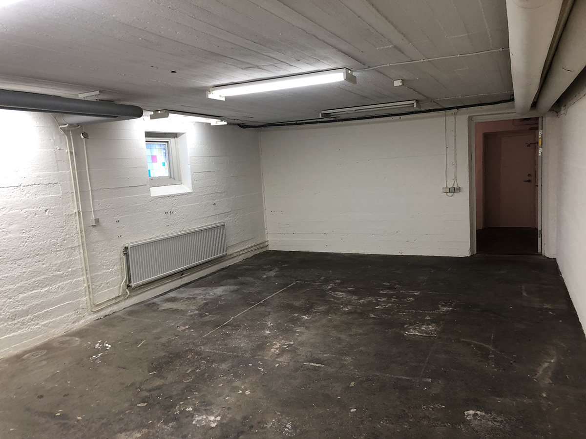 Rum i lokal med vitmålade väggar och litet fönster med mosaikrutor