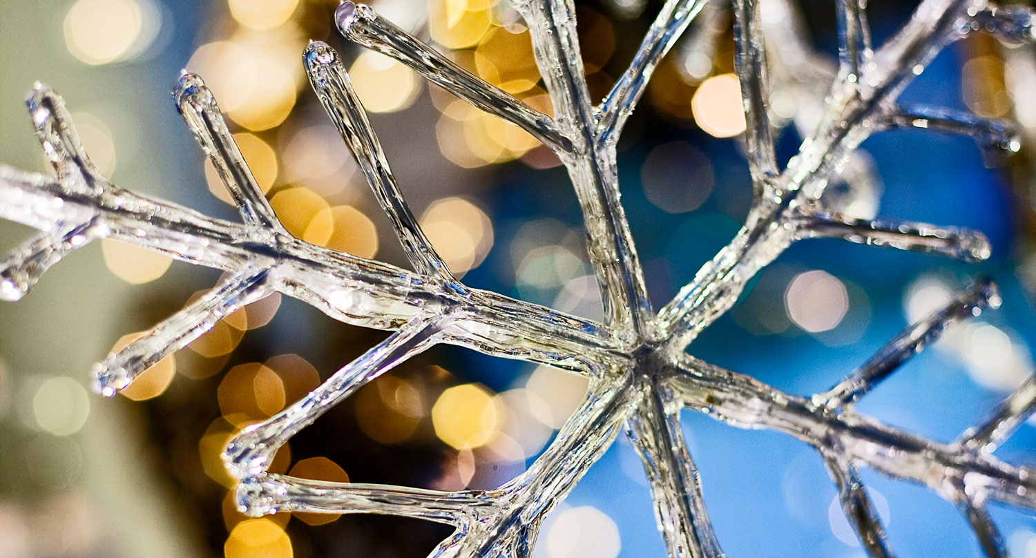 Snöflinga i glas med julbelysning bakom