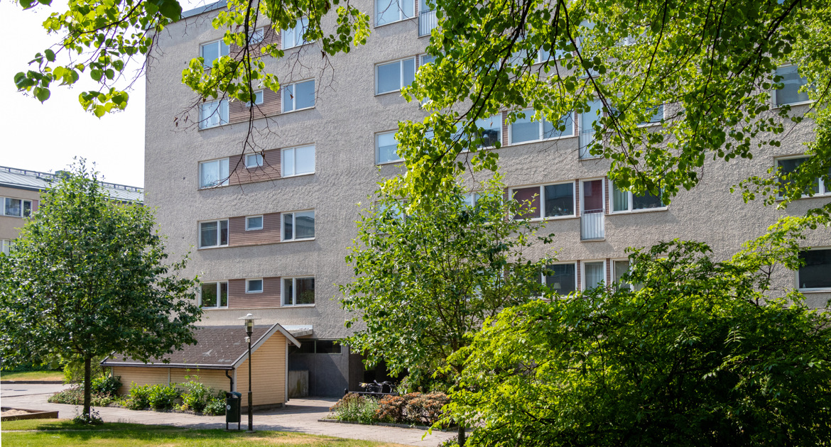 Hus på Drottninggatan med grönskande innergård med flera stora träd.