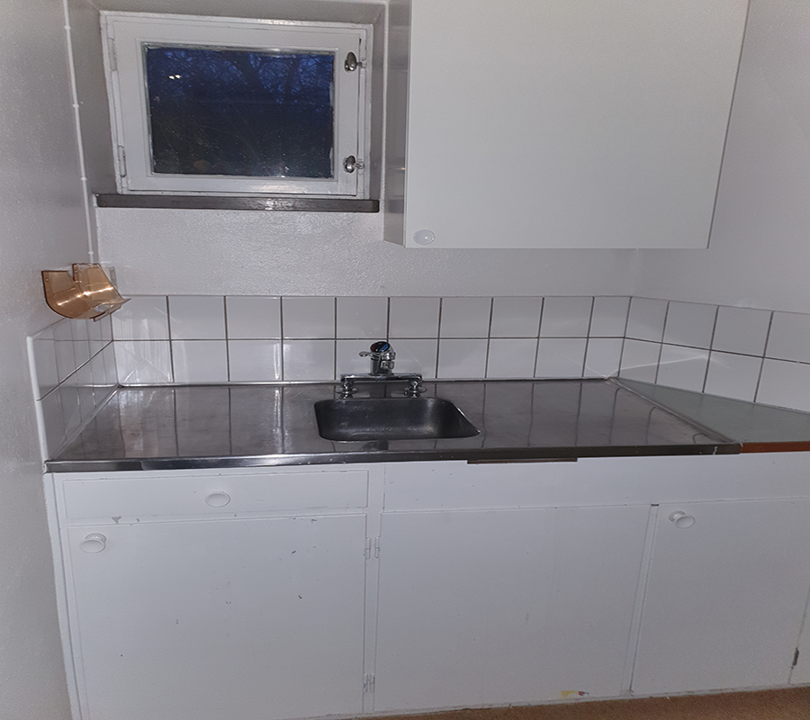 Köksdel med vita skåpsluckor och diskho