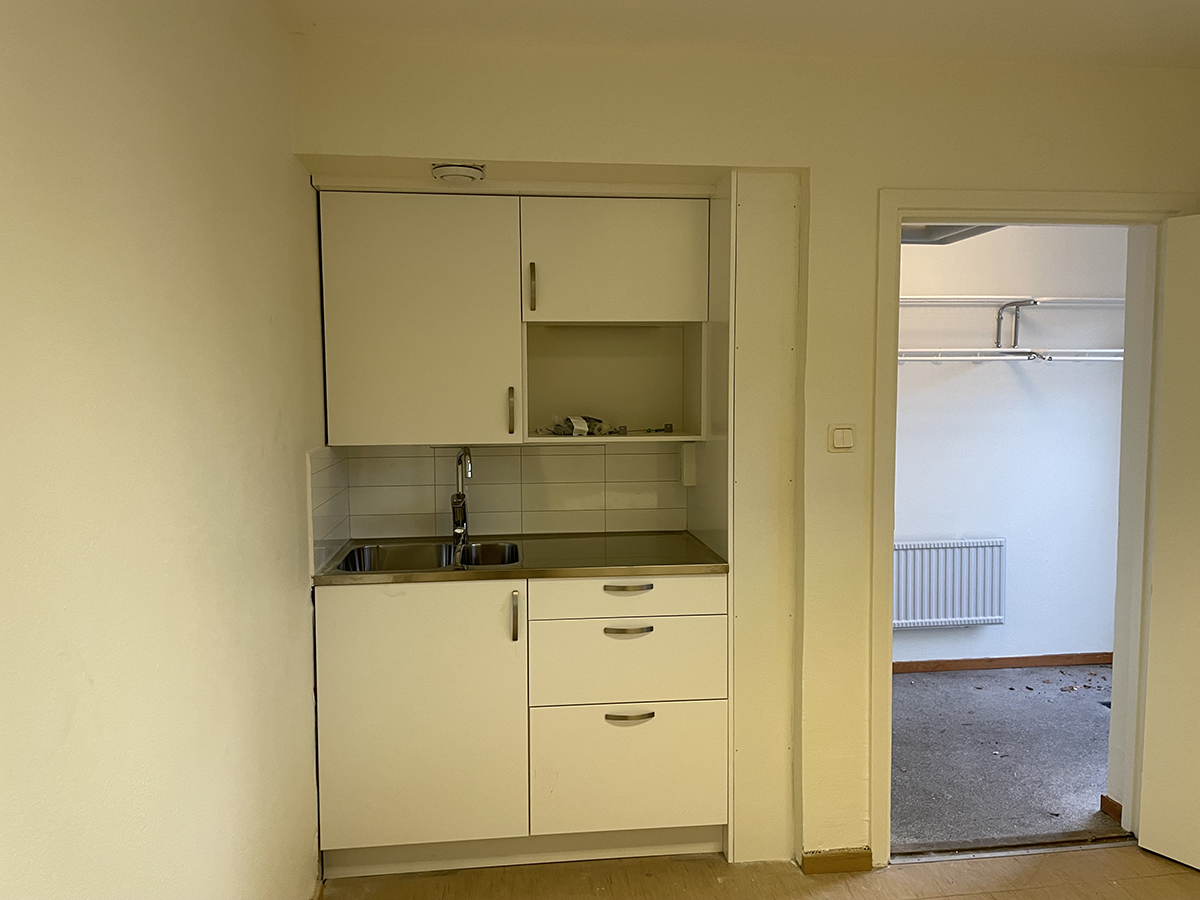 Del i kontorslokal med litet pentry och vitmålade väggar