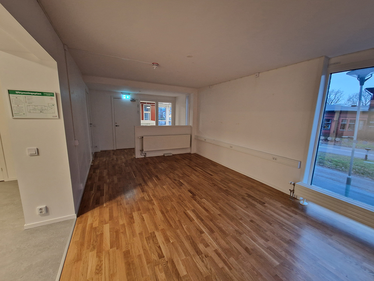 Del i lokal med större rum med vita väggar och parkettgolv