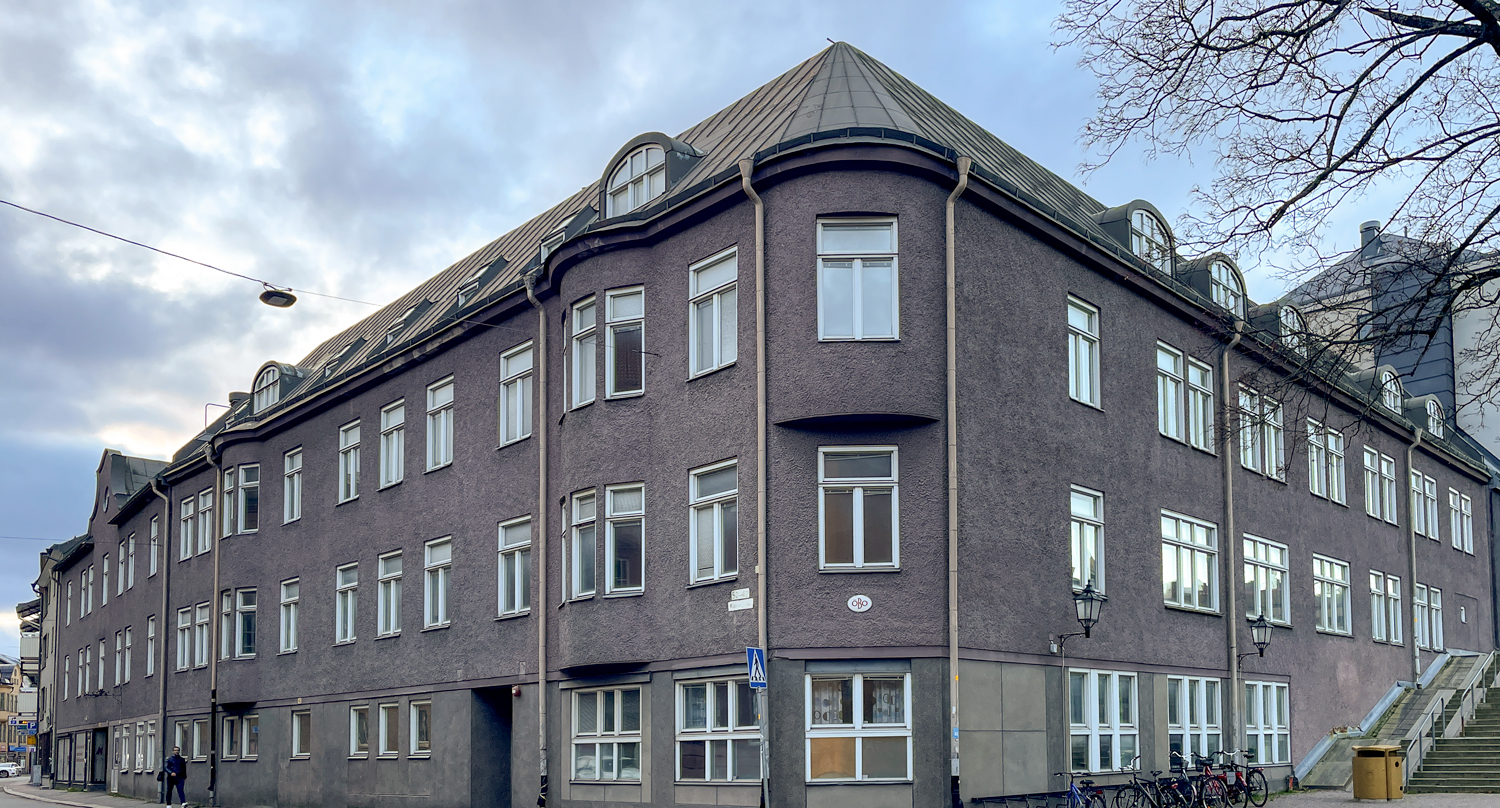 Fastighet i två våningar med fönster i äldre stil och fasad i grålila.