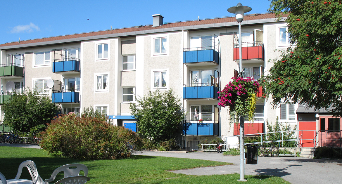 Fastighet i tre våningar med färgglada balkonger i rött och blått.