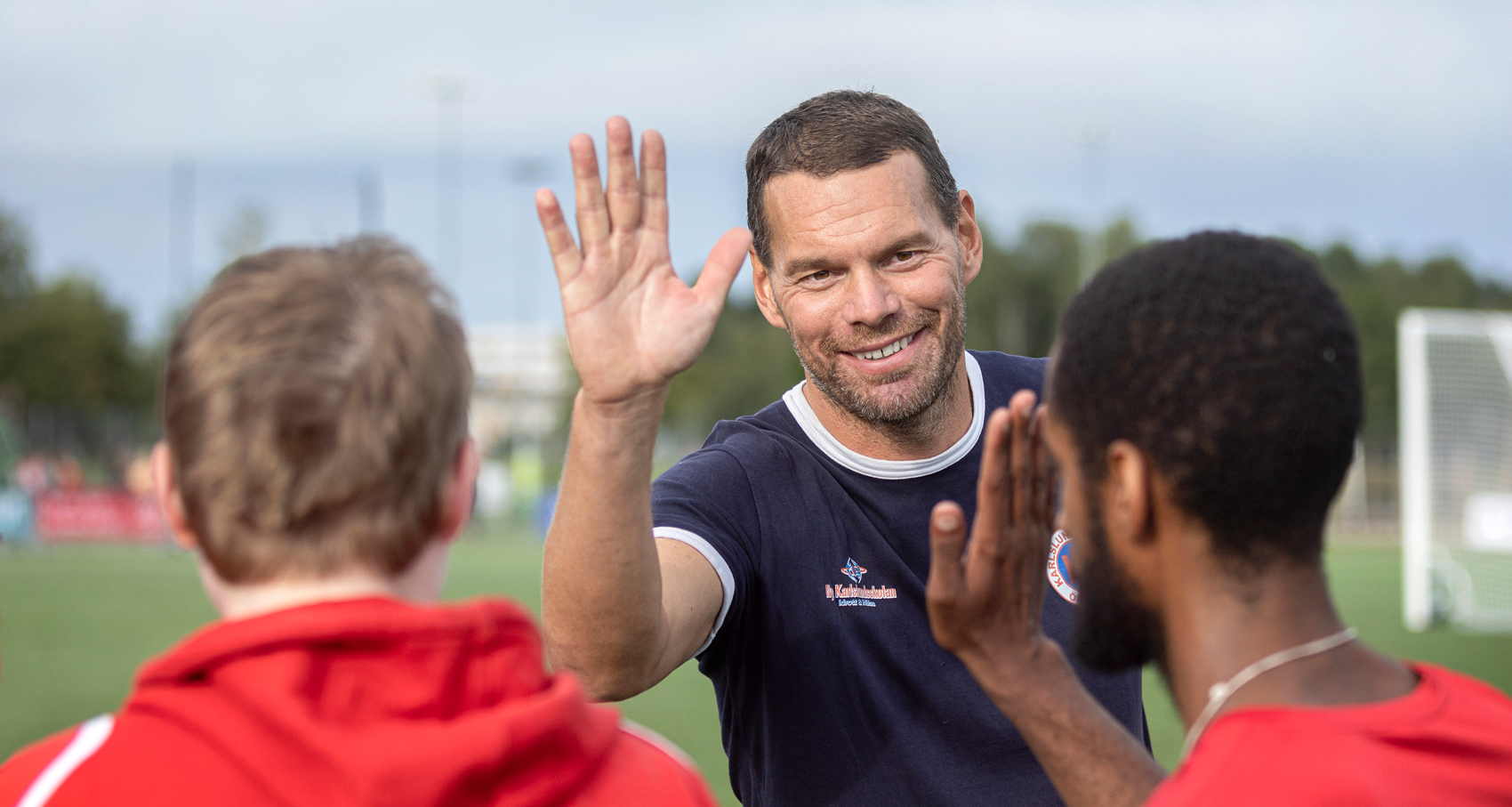 Tränare i Karlslund United gör high five med två spelare i laget.
