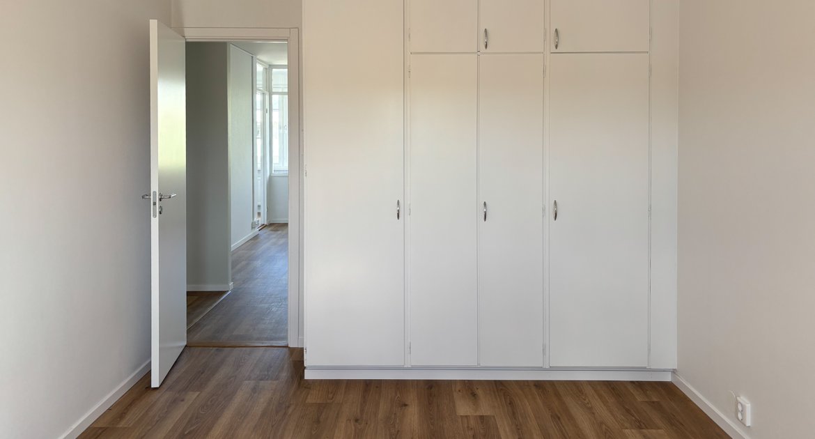 Sovrum med inbyggda garderober och vitmålade väggar.