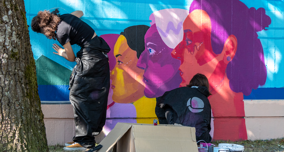 Två ungdomar målar en färgstark muralmålning i Markbacken