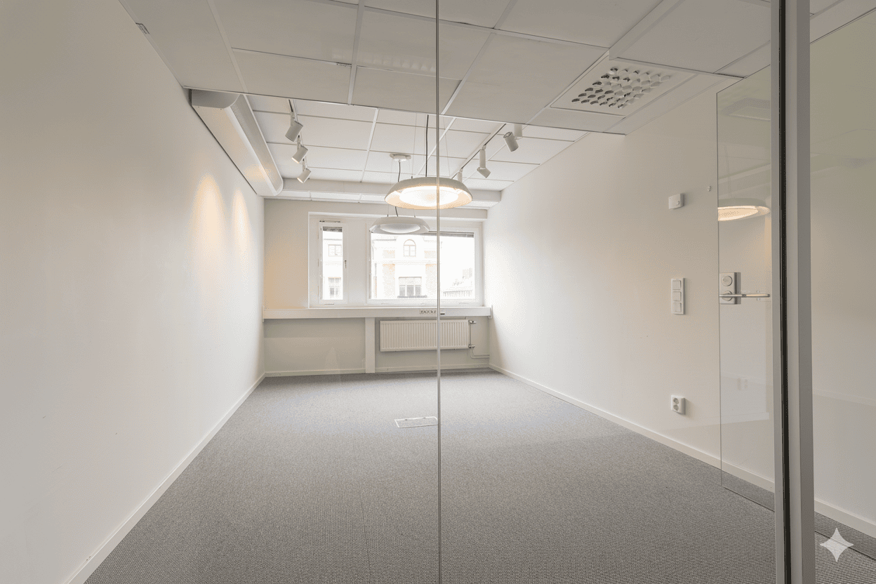 Litet kontorsrum med ljusa väggar, grå heltäckningsmatta och glasvägg med dörr.