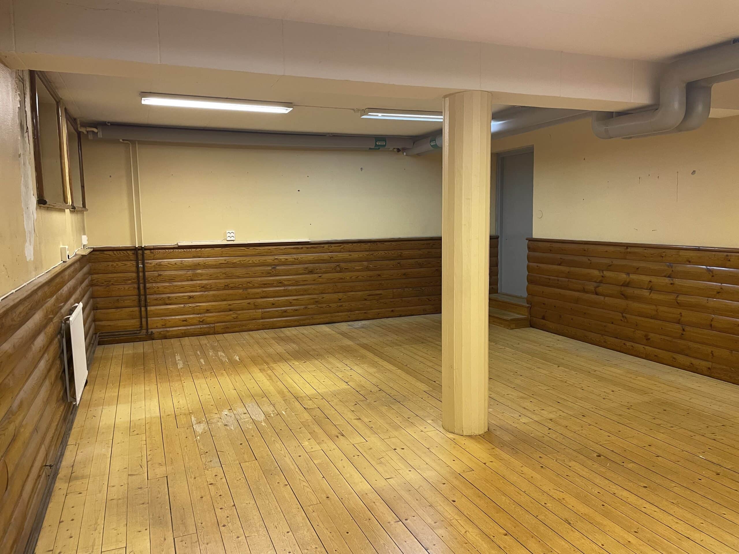 Lokal med trägolv och panel på vägg.