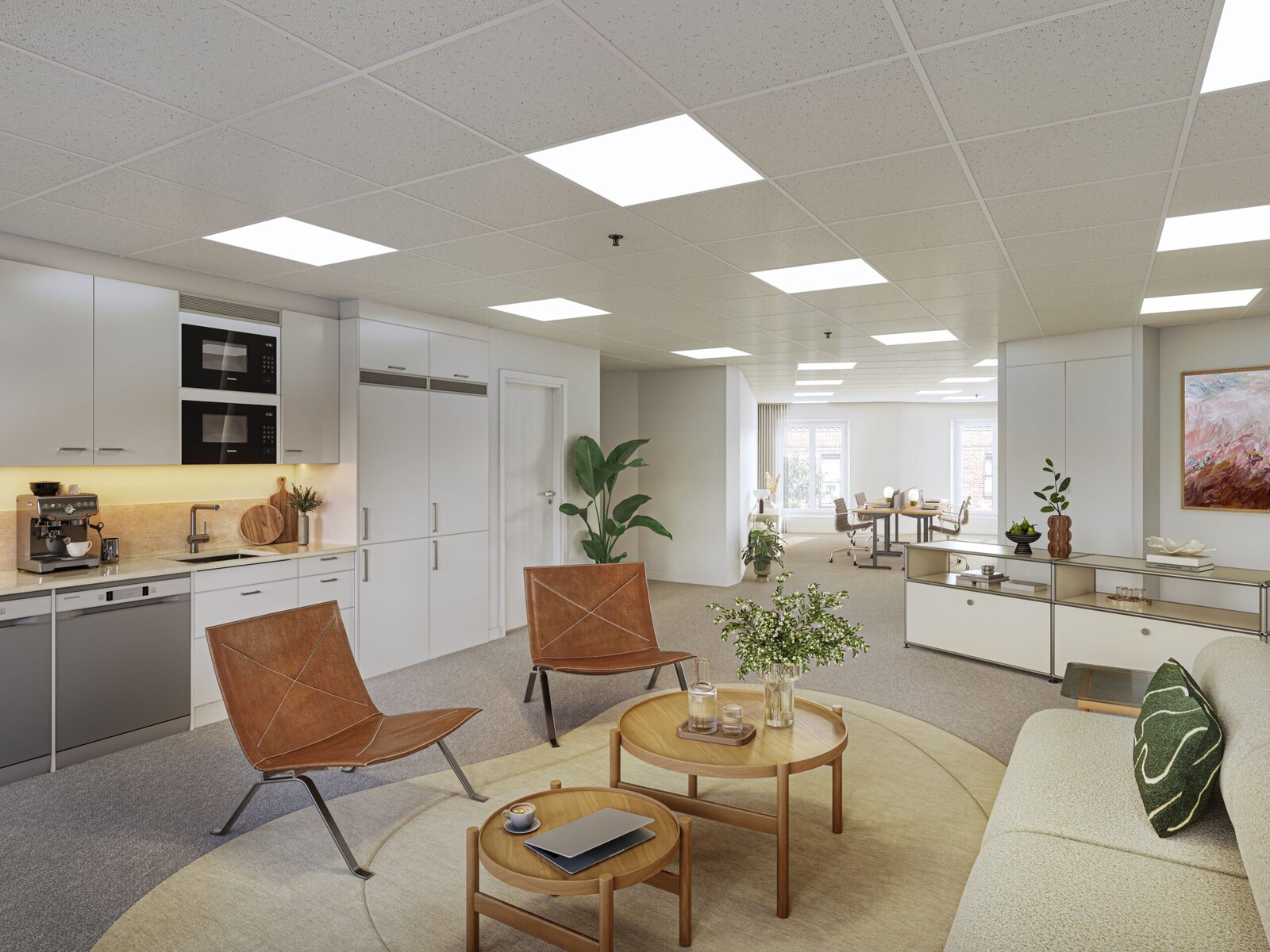 Ett öppet och modernt kontorsutrymme med pentry i ljusa färger, sittgrupp med fåtöljer och soffbord, växter och förvaring samt arbetsplatser längre in i rummet under ett ljust innertak.