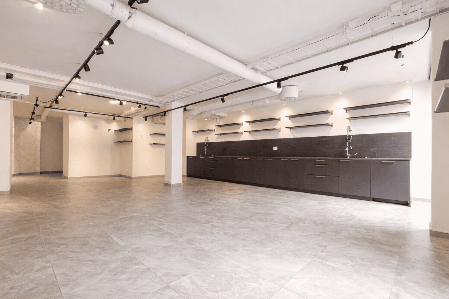 Lokal med stengolv och en lång bänk i mörk trä längst in.