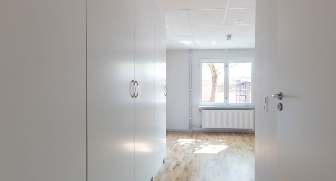 Hall med garderober som leder in till ett rum på Studentgatan.