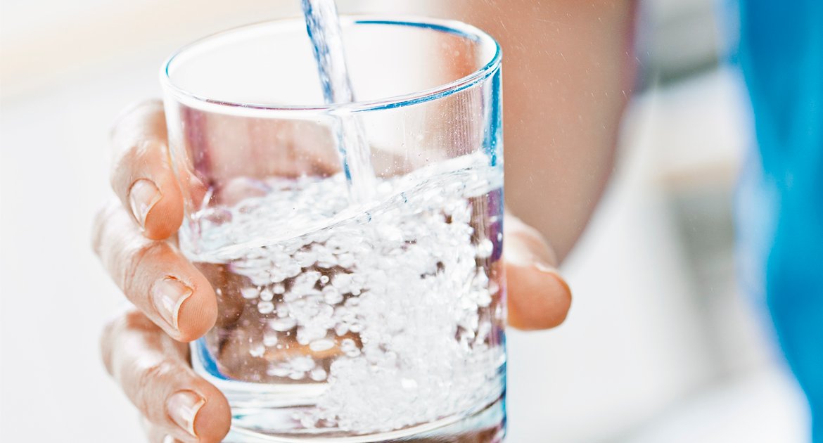 Hand som håller ett glas med vatten