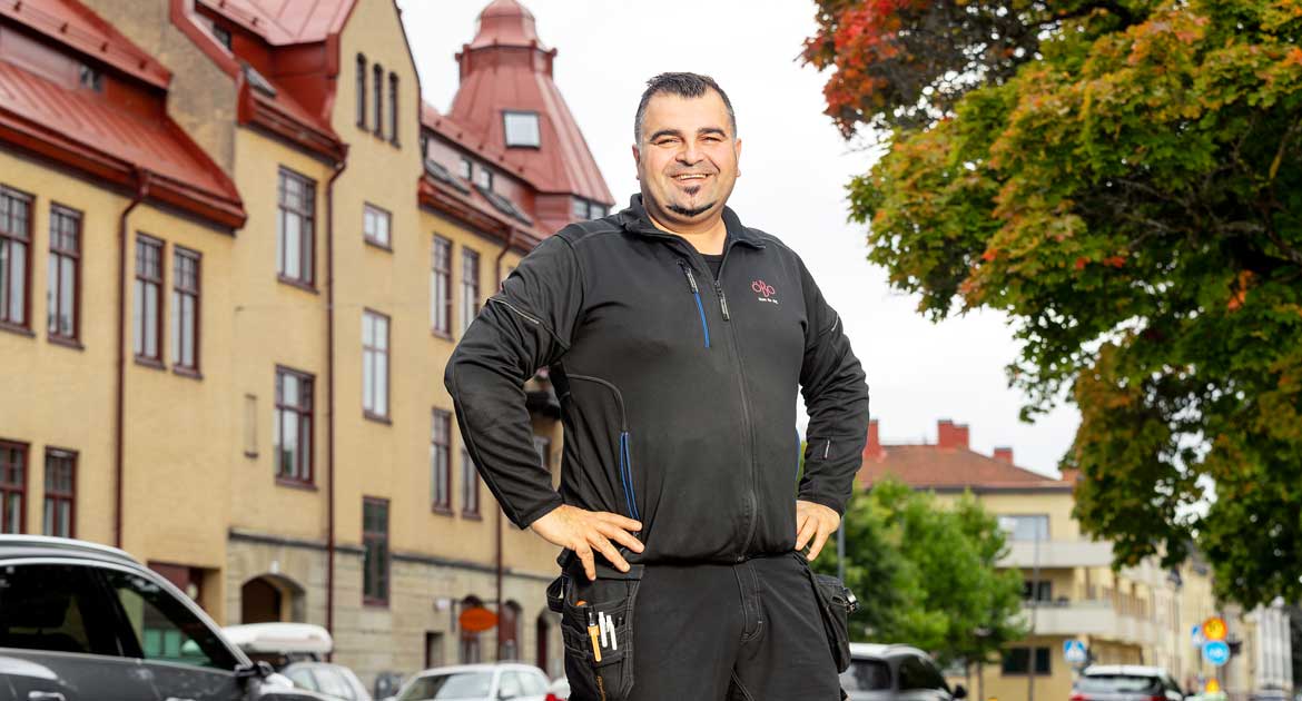 Manlig medarbetare på ÖBO står utanför ett hus och ler in i kameran.