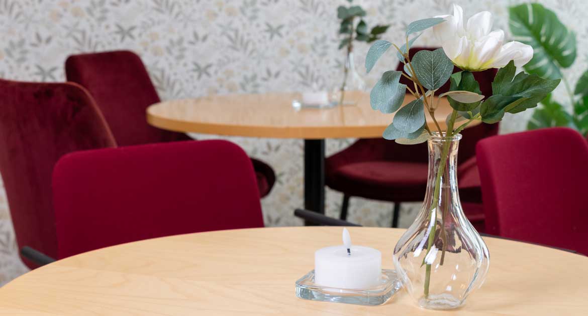 En vas med blommor och ett ljus på ett bord.