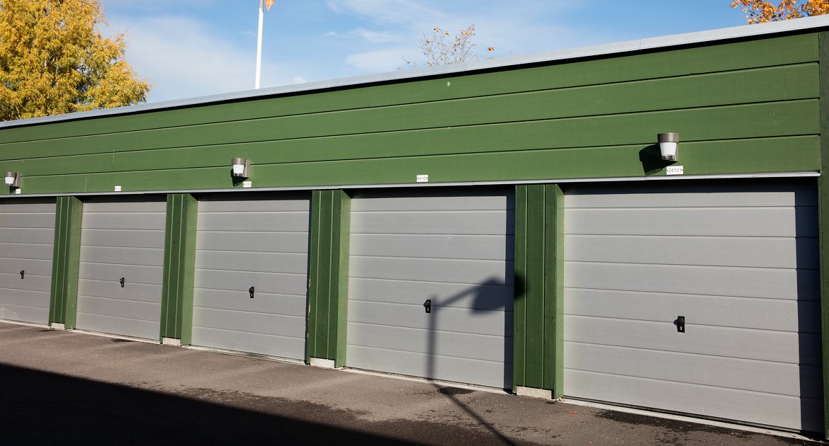 Grön garagelänga med beige dörrar.