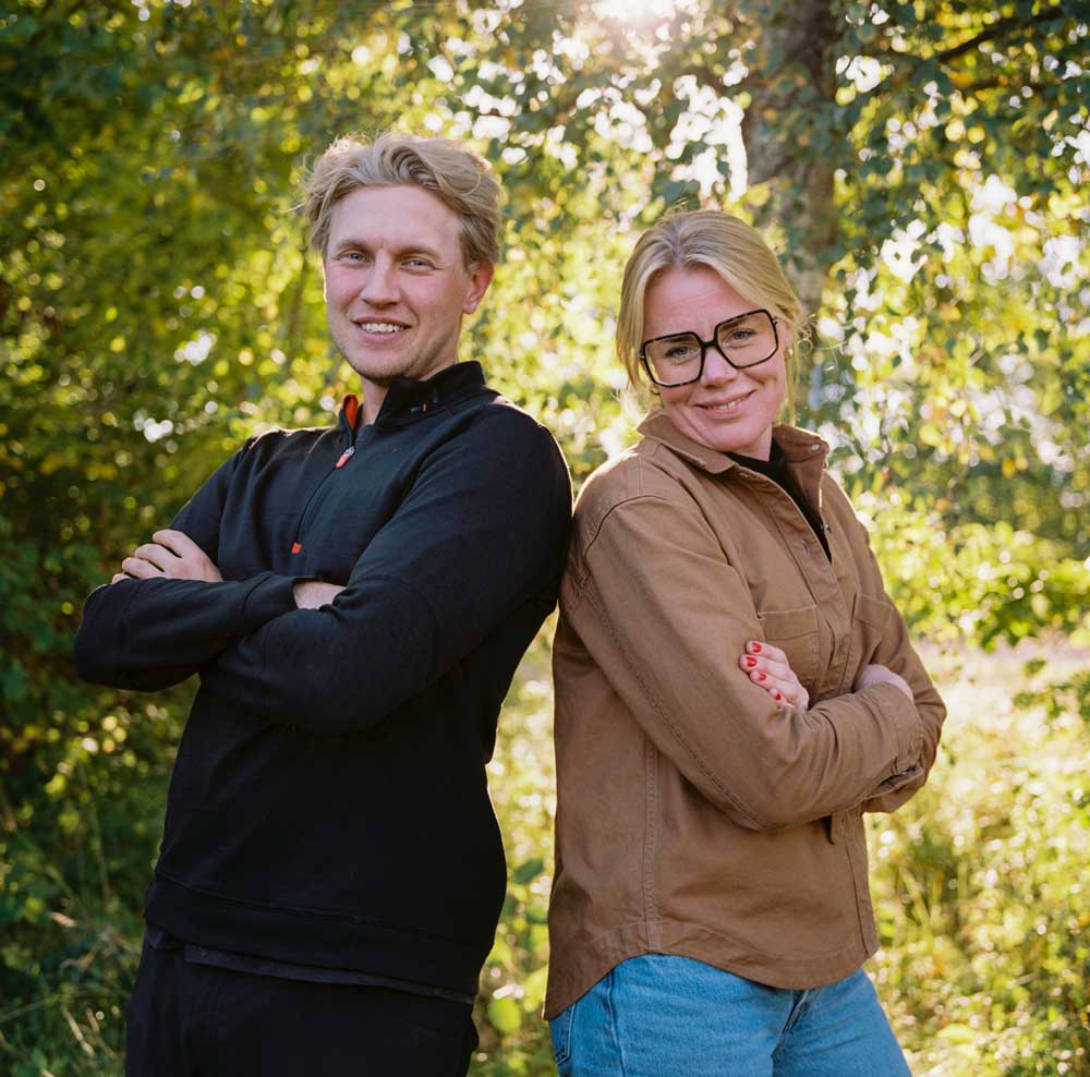 Jim Holmgren och Anna Maria Hellner står rygg mot rygg och ler in i kameran.