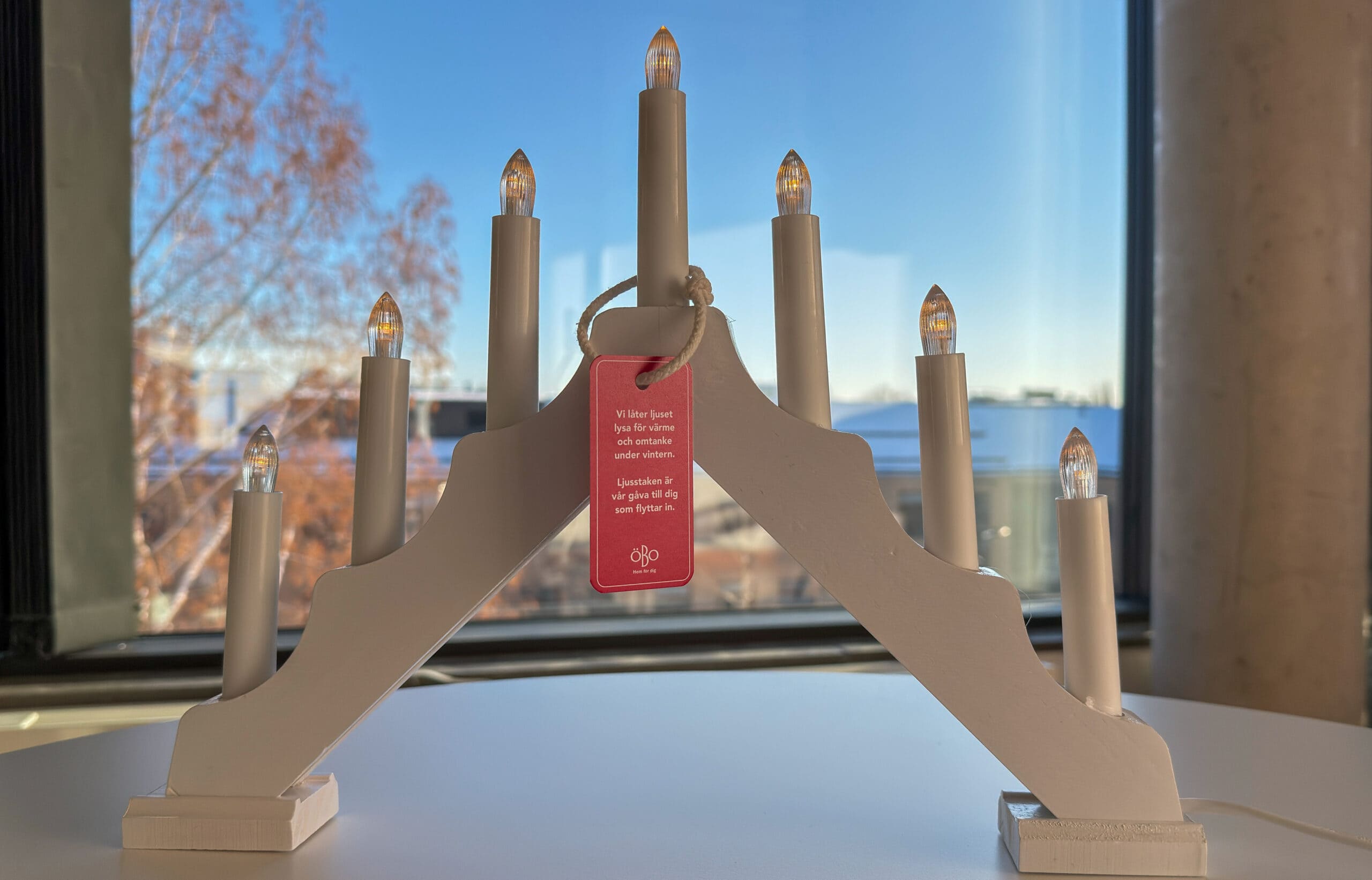 Adventsljusstake mot fönster, fortfarande ljus ute