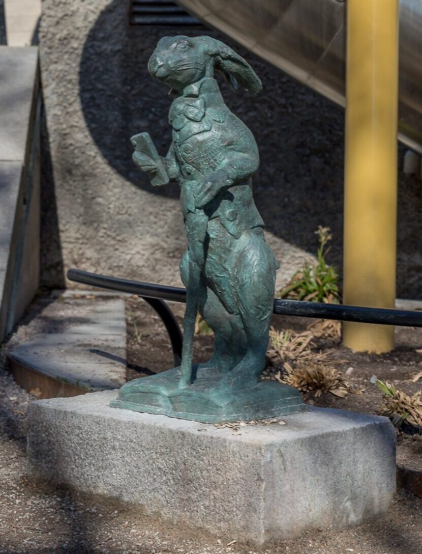 Närbild på konstverket Underlandet, en kanin i brons som håller i en mobiltelefon.