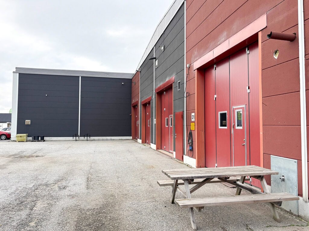 Industrilokal med flera röda lastportar längs fasaden och uppställningsyta utanför.