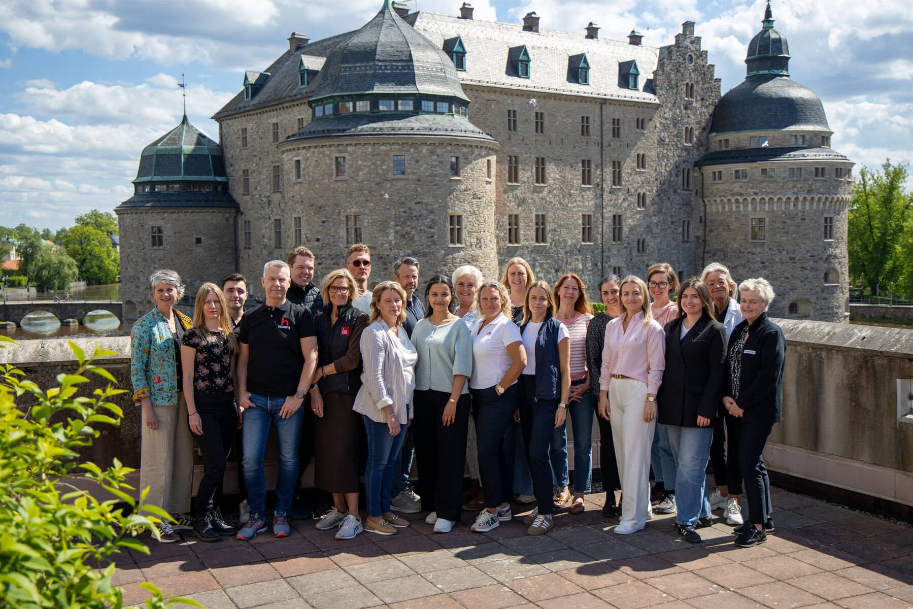 Ett tjugotal personer står på en terrass med Örebro slott i bakgrunden.